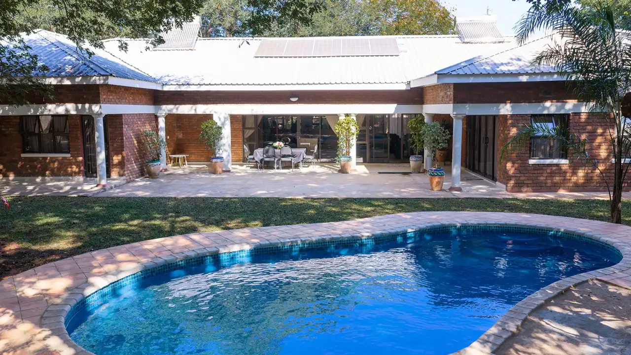 Cosmo Guest House and its blue swimming pool in a leafy garden